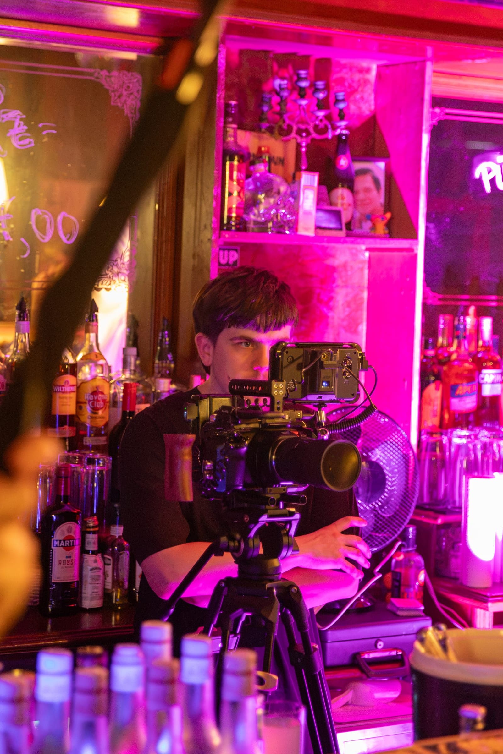 Kameramann arbeitet hinter einem Rig an einem pink beleuchteten Set