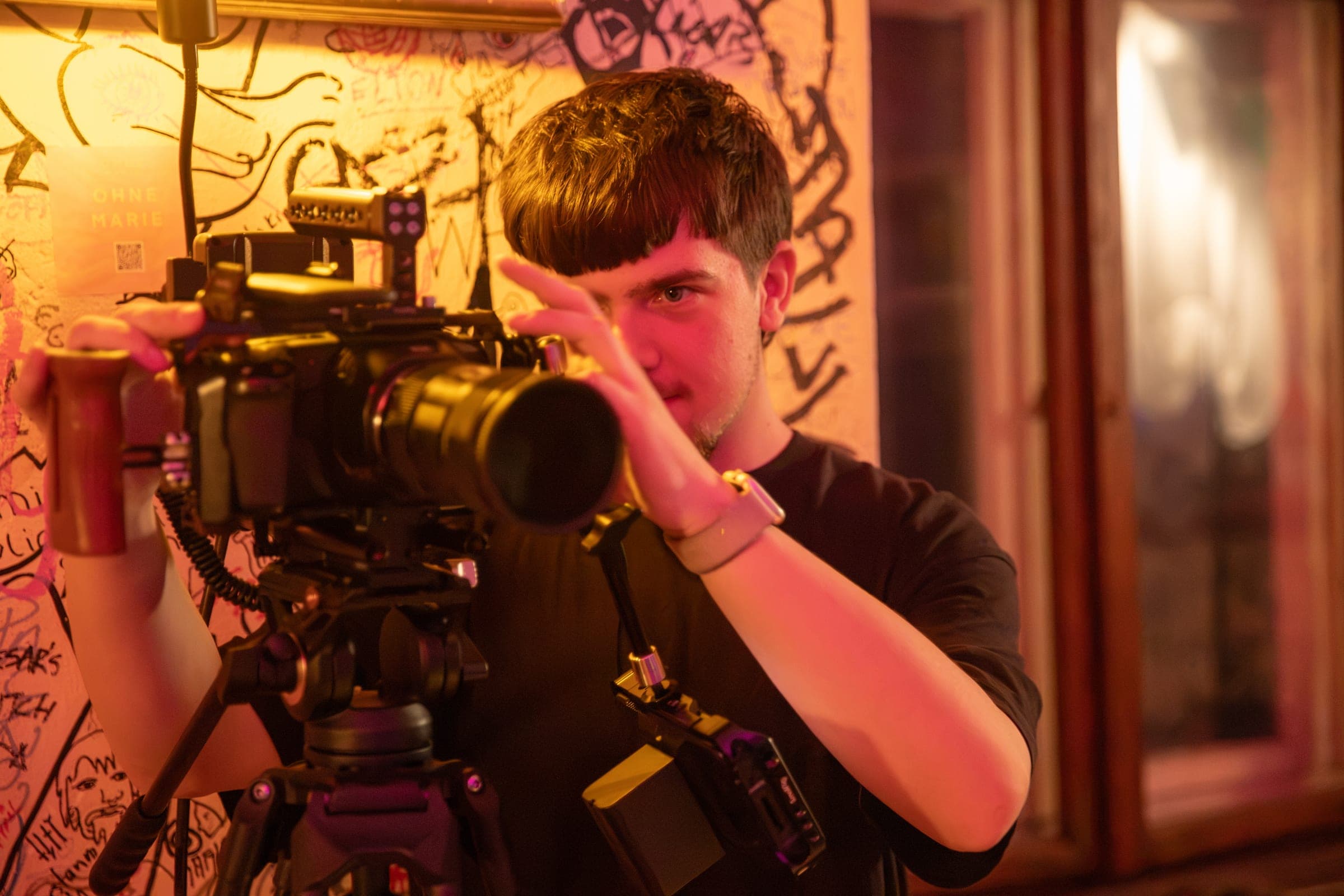 Kameramann richtet eine professionelle Filmkamera an einem beleuchteten Set ein